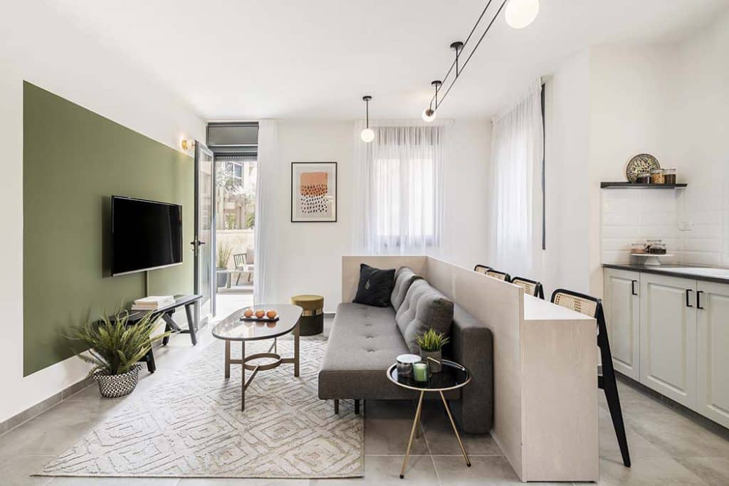 Living room with a sofa, television and a door onto a terrace in a furnished apartment at Mr. Agrippa, Jerusalem