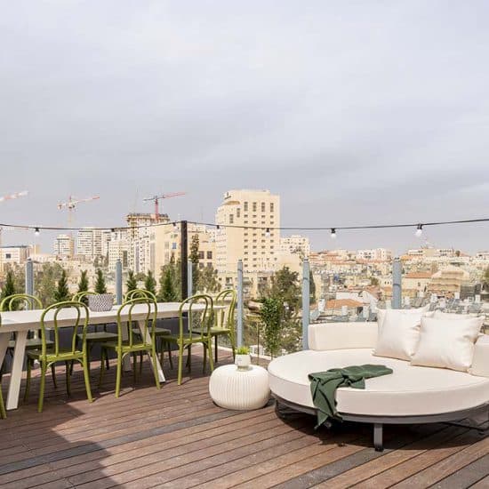Shared rooftop terrace of Mr. Agrippa with a dining table and daybed looking over central Jerusalem