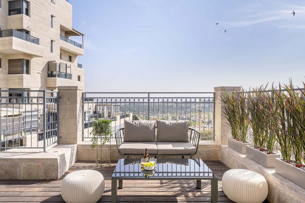Private terrace with a sofa and planters at Mr. Agrippa in Jerusalem, looking out over the neighbourhood