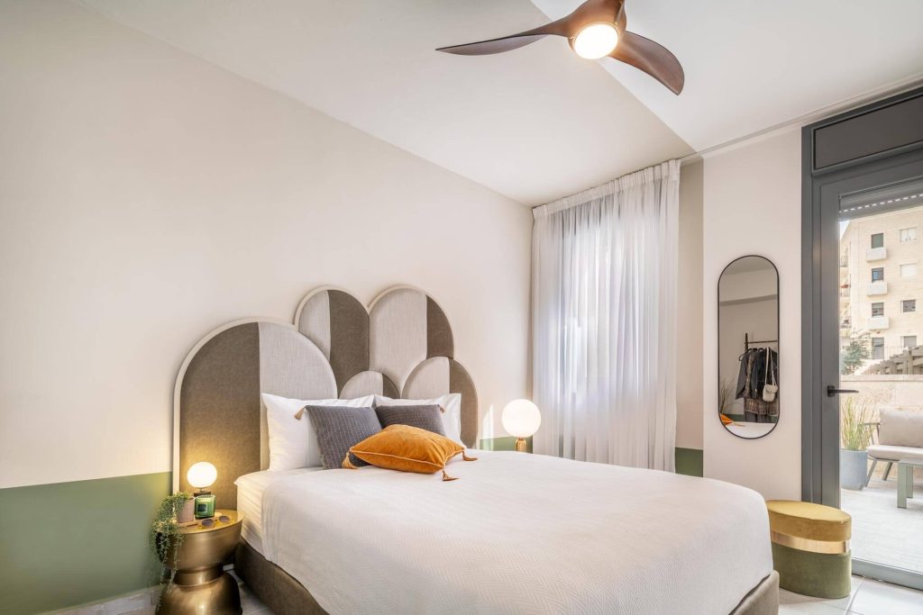 Bedroom at Mr. Agrippa in Jerusalem with an upholstered headboard, ceiling fan and a door onto the balcony