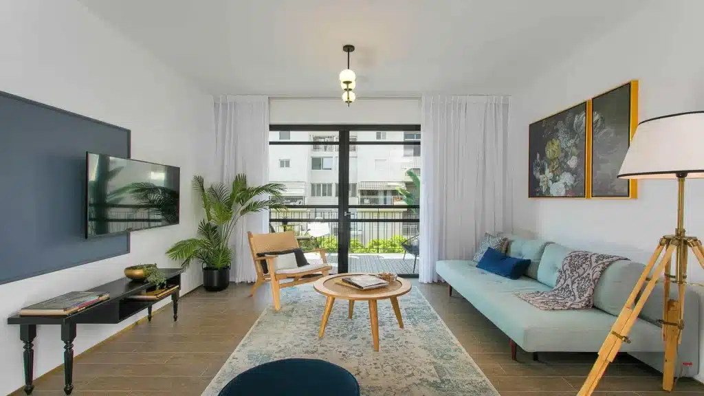 Furnished living room with a sofa, armchair and balcony door in a TLV2GO serviced apartment in Tel Aviv