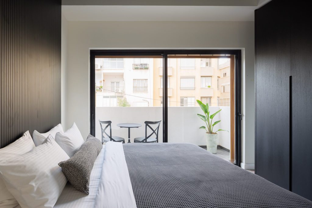 Bedroom with a door onto a balcony in a TLV2GO serviced apartment in Tel Aviv